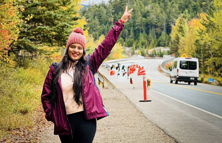 Sai Navudu standing on side of road holding up hand displaying peace sign with fingers