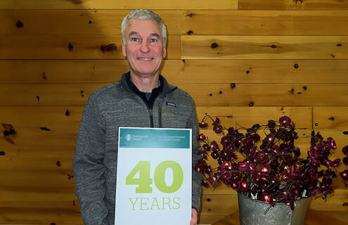 Roger Parent holds a sign indicating his 40 years of employment at MAHHC